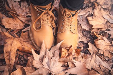 Sonbahar parkında kahverengi çizmeli bir kadının bacakları..