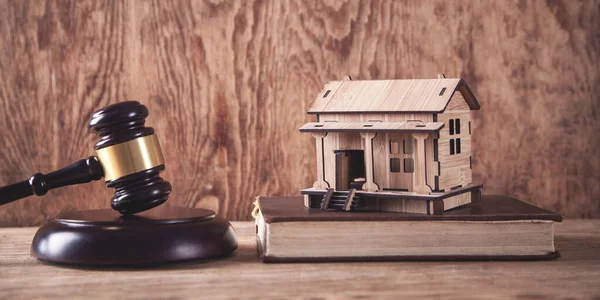 Judge gavel with a wooden house model.