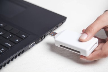 Masasında dizüstü bilgisayarı olan USB belleği tutan bir kız..