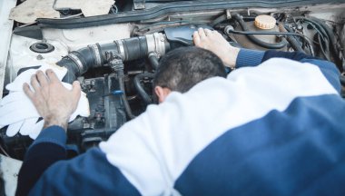 Beyaz adam arabasının motoruna bakıyor..