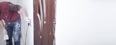 İşçi duvarı zımpara kağıdıyla öğütüyor. Yenileme