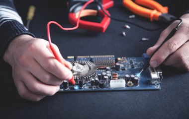 Adam çoklu metre ile bilgisayarı kontrol ediyor..
