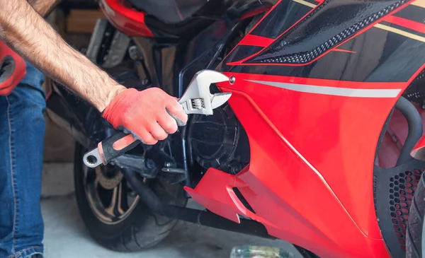 Mechanic using a wrench on a motorcycle. Garage. Work