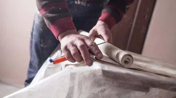 Worker cutting wallpaper. Apartment repair