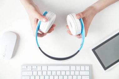 Ofis masasında kulaklık tutan eller. Müzik dinlerken