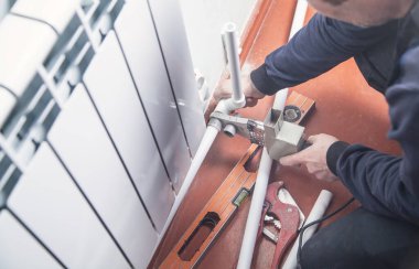 Plastik boruları bağlayan bir işçi. Su ısıtma radyatörü kuruluyor