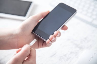 İş kadını ofiste akıllı telefonu şarj ediyor..