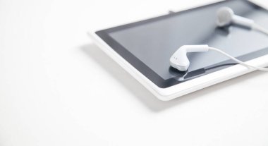 Beyaz masasında kulaklık olan tablet..