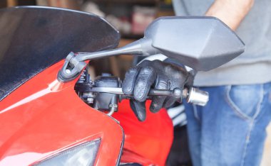 Siyah eldivenli beyaz bir motosikletli. Hobi