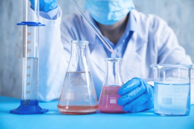 Laboratuvarda şişeyle çalışan bir kız..