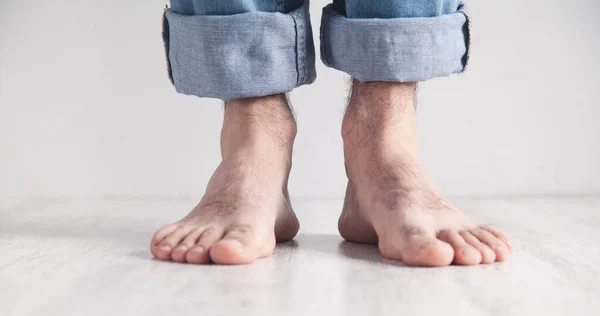 Male feet stand on white floor.