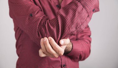 Dirsek ağrısı olan beyaz bir adam. Ağrı kesici kavramı