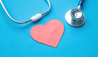 Mavi arka planda steteskoplu kırmızı kalp..