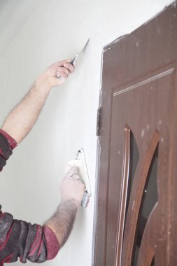 İşçi duvarı zımpara kağıdıyla öğütüyor. Yenileme