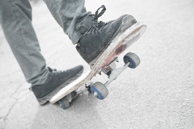 Çocuk asfaltta kaykay sürüyor..