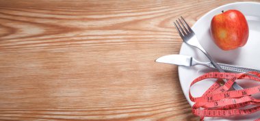 Elma beyaz tabakta. Çatal ve bıçakla mezura ölçüyorum. Diyet, Sağlık