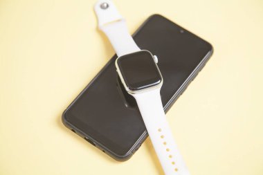 Sarı arka planda akıllı saat ve akıllı telefon. Kişisel cihaz. Teknoloji