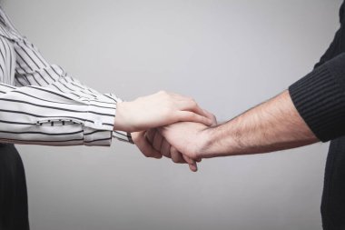 Erkek ve kadın elleri gri arkaplanda.