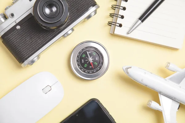 Sarı arkaplanda pusula ve diğer nesneler var. Seyahat