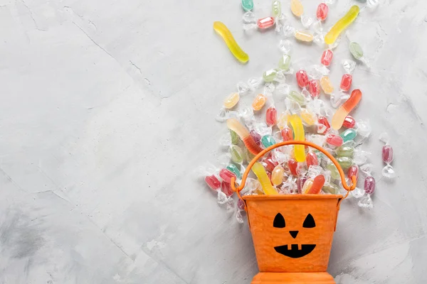 Halloween bucket with candies and jujube on gray concrete backgr — Stock fotografie