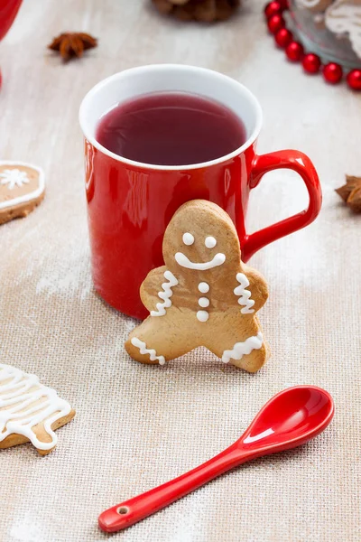 Chá, biscoito de gengibre e colher vermelha no fundo de madeira compensada . — Fotografia de Stock