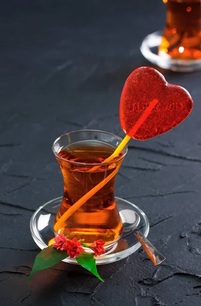 Glass cup with a tea and candy heart — Stock Photo, Image