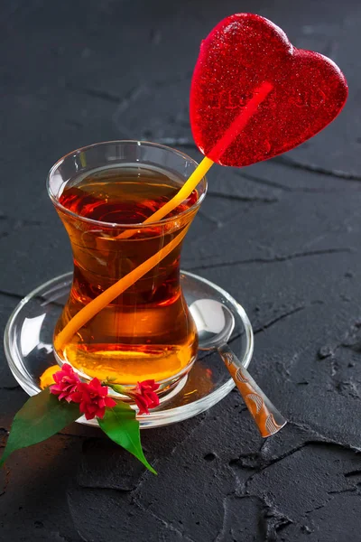 Glass cup with a tea and candy heart — Stock Photo, Image