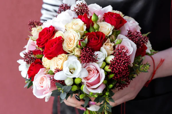 Young florist holding wedding bouquet of roses.