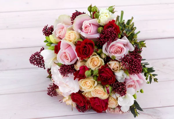 Beyaz ahşap zemin üzerinde farklı çiçekler gelin buketi.