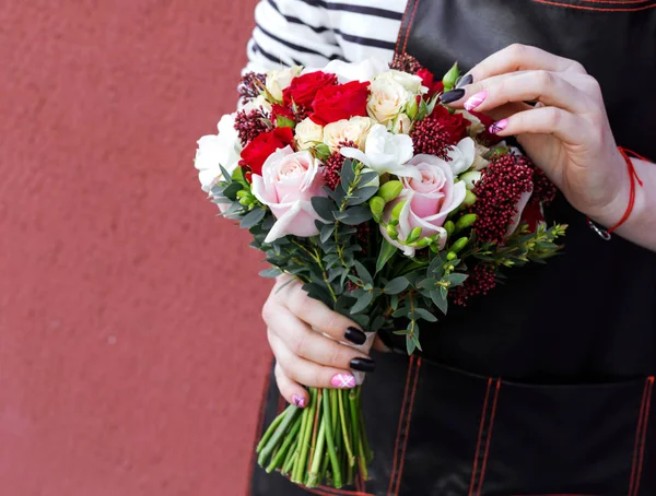 Young florist holding wedding bouquet of roses.