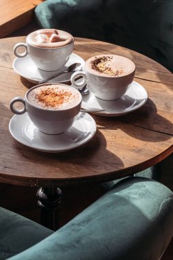 Kafedeki masada büyük beyaz bardakta kakao. Şekerleme, biber ve tarçınlı kakao..