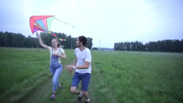 Pareja joven corriendo en el campo verde con una cometa — Vídeos de Stock