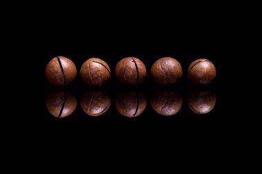 Siyah yansıtıcı arka plan beş macadamia fındık