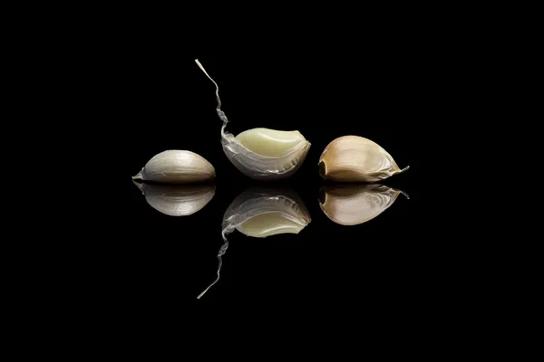 Tres ajos pelados sobre fondo negro — Foto de Stock