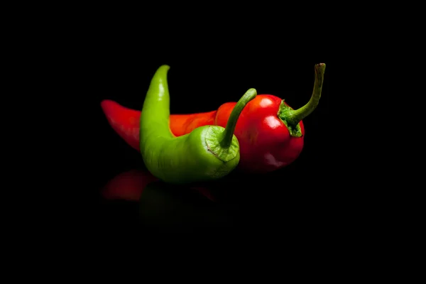 Piros és zöld paprika, fekete háttér — Stock Fotó
