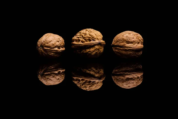 Tre hela valnötter isolerad på svart bakgrund — Stockfoto
