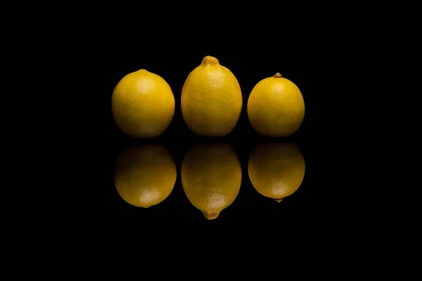 Tre helt isolerade gula citroner på svart bakgrund — Stockfoto