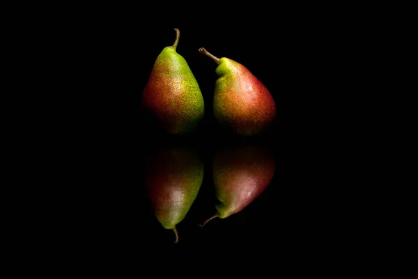 Dos peras rojas y verdes enteras aisladas sobre fondo negro — Foto de Stock