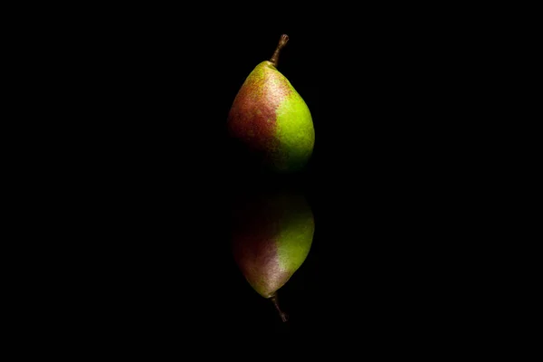 Uma pêra vermelha e verde inteira isolada no backgr reflexivo preto — Fotografia de Stock