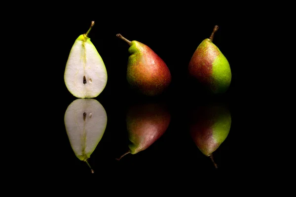 Un corte por la mitad y dos peras rojas y verdes enteras aisladas en bl — Foto de Stock