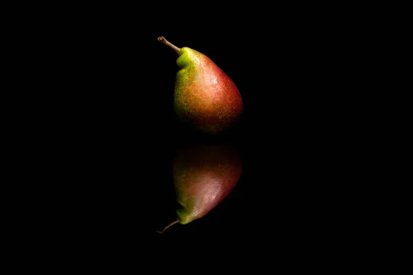 Satu buah pir merah dan hijau utuh terisolasi pada backgr reflektif hitam — Stok Foto