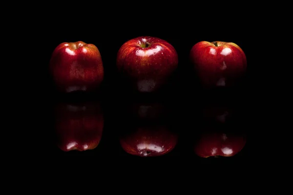 Tres manzanas rojas aisladas sobre fondo negro — Foto de Stock