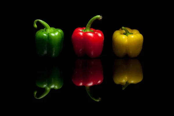 Три цілих болгарських перцю жовтий зелений червоний ізольовані на чорній спині — стокове фото