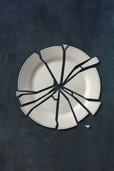 Broken white plate isolated on gray slate stone background — Stock Photo, Image