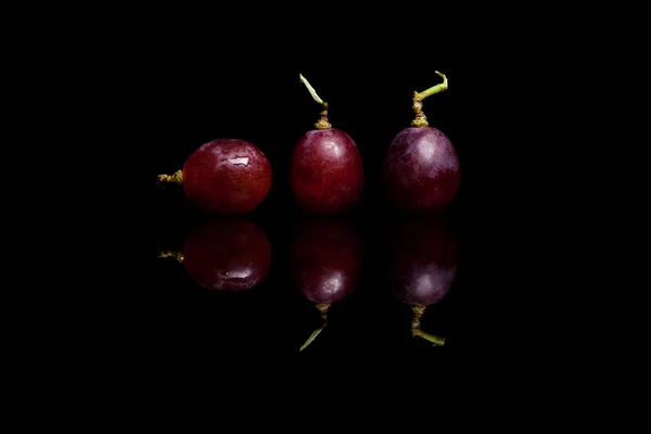 Tres uvas rojas aisladas sobre fondo negro —  Fotos de Stock