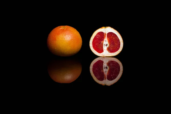 Ganze und in Scheiben geschnittene Grapefruit isoliert auf schwarzem Hintergrund — Stockfoto