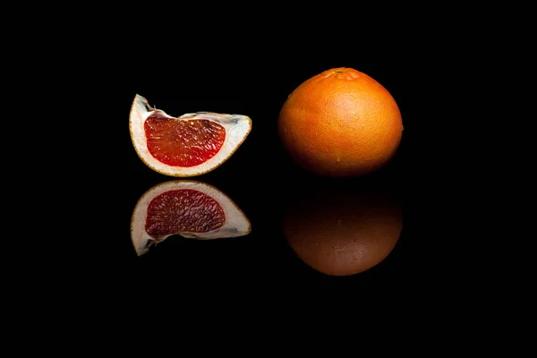 一个整体和葡萄柚孤立在黑色背景上的一片 — 图库照片
