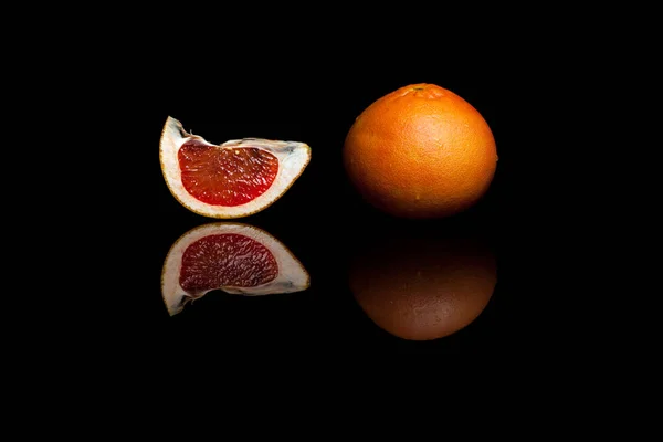 Egy egész és egy szelet grapefruit elszigetelt fekete háttérb Stock Fotó