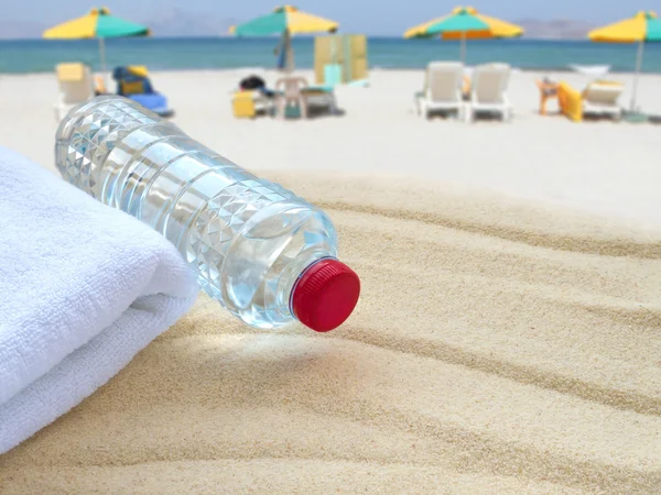 Пляшка мінеральної води та рушник на громадському пляжі — стокове фото