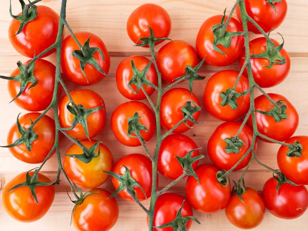 Three tomato bunches on the wooden background — Stock Photo, Image